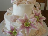 a white beach wedding cake with seashells, starfish of sugar and faux blooms for a beach tropical wedding