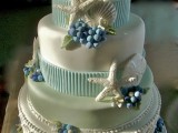 a shiny white wedding cake with light blue ribbons, sugar berries, starfish, patterns looks very quirky and unusual