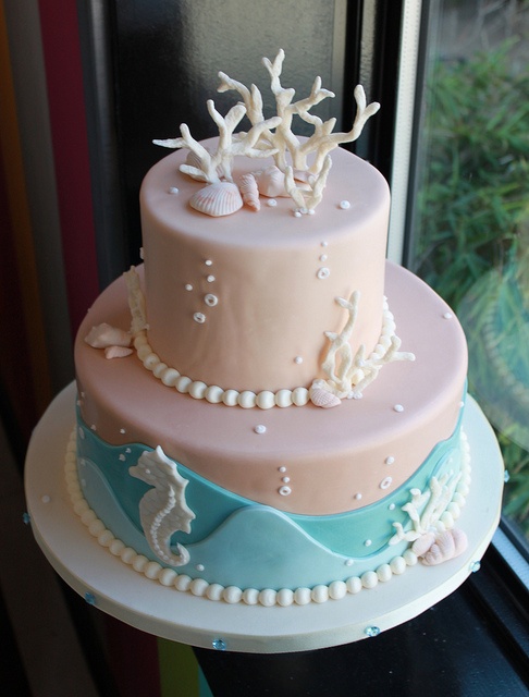 a blush beach wedding cake with blue waves, pearls, bubbles, seashells and corals of sugar looks bright and very catchy
