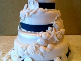 a nautical wedding cake in white, with navy ribbons, sugar seashells, starfish and urchins is very bold and contrasting