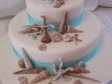 an elegant white wedding cake with turquoise ribbons, sugar seashells and starfish is a lovely modern wedding idea