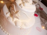 a white beach wedding cake with coral patterns, sugar seashells and starfish on top for an elegant beach wedding