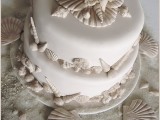 a neutral beach wedding cake with sugar seashells of various kinds looks relaxed and cool