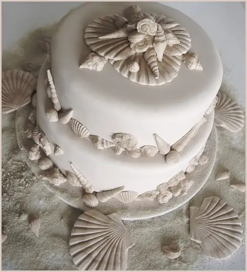 a neutral beach wedding cake with sugar seashells of various kinds looks relaxed and cool