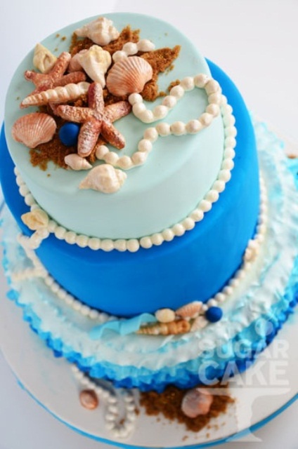 a bright blue color block wedding cake with sugar pearls, starfish, seashells and beach sand is lovely and bold