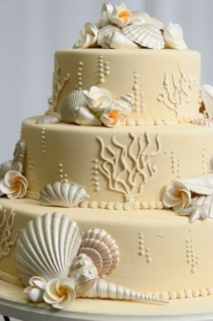 a tan beach wedding cake with coral patterns, pearls, seashells and sugar blooms looks non-typical and the color reminds of beach sand