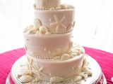 a blush beach wedding cake with sugar starfish, seashells, pearls and other stuff in white is a gorgeous idea for a beach wedding