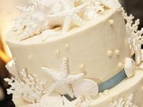 a white textural wedding cake with edible pearls, starfish, corals, seashells and ribbons is a classic option for a beach wedding