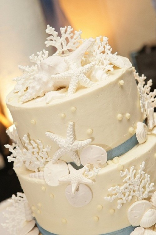 a white textural wedding cake with edible pearls, starfish, corals, seashells and ribbons is a classic option for a beach wedding