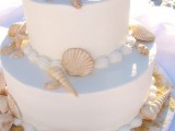 a white beach wedding cake with seashells, of sugar and real ones, and edible pearls
