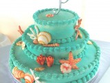 a colorful emerald beach wedding cake with sugar corals, starfish, seashells in red and white is a fun idea