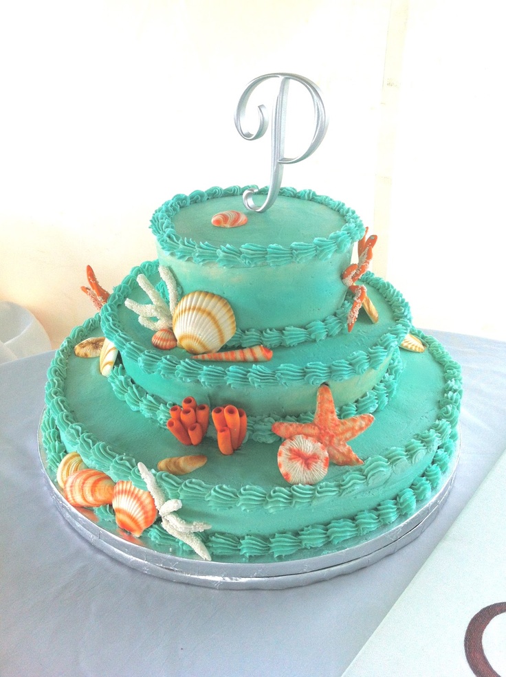 A colorful emerald beach wedding cake with sugar corals, starfish, seashells in red and white is a fun idea