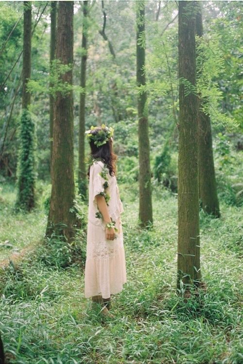 a woodland boho bride wearing a neutral A-line lace midi dress, boots and a greenery crown going down the arm