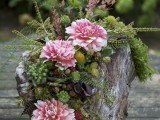 a tree stump decorated with lush greenery, pink blooms and berries is  lovely boho woodland decoration or a centerpiece