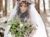 a boho woodland bride wearing a bold wildflower crown and carrying a greenery and berry bouquet