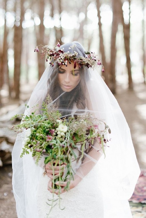 a boho woodland bride wearing a bold wildflower crown and carrying a greenery and berry bouquet