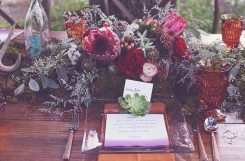 a woodland boho wedding centerpiece of berries, bright blooms, antlers, moss and lots of greenery is a very wild and cool idea
