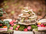 a woodland food display –  a moss runner with apples and bright blooms, wood slice stands and chargers look super cool