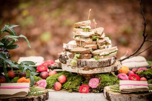a woodland food display -  a moss runner with apples and bright blooms, wood slice stands and chargers look super cool