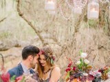 a bright boho woodland wedding tablescape with bold floral arrangements and berries, crystals and candles over the table and touches of gold