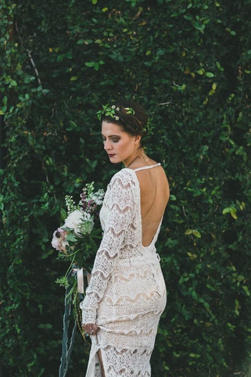 a boho woodland bride in a boho lace sheath wedding dress with an open back, a side slit and a greenery crown is lovely