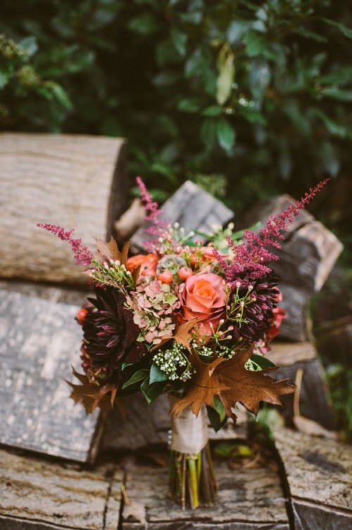 a bright fall wedding bouquet for a boho or woodland bride with dried leaves, bold blooms and some greenery
