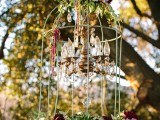 a boho vintage decoration of a cage, with a mini chandelier inside, bold blooms and greenery is lovely