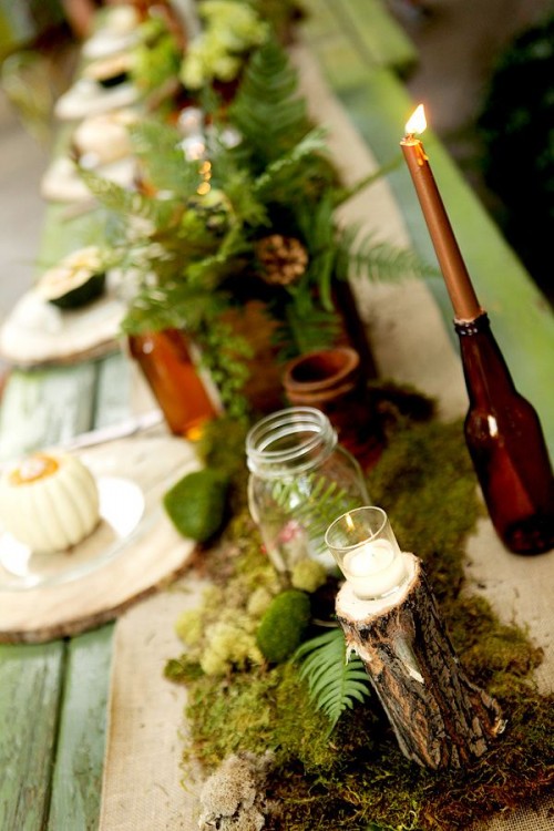 a woodland table runner of moss, candles in glass jars, greenery and ferns for a woodland tablescape