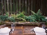 a woodland wedding centerpiece of a rough wooden bowl filled with moss and greenery is a cool and simple idea