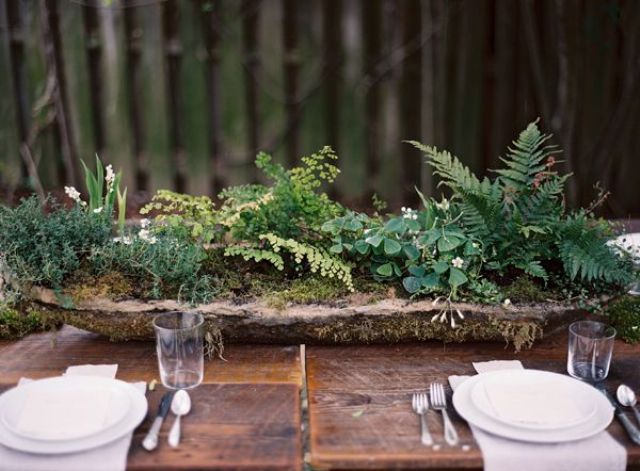 A woodland wedding centerpiece of a rough wooden bowl filled with moss and greenery is a cool and simple idea