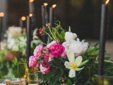a romantic wedding centerpiece of black candles in gold candle holders and lush pink and white blooms
