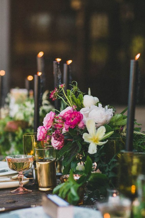 a romantic wedding centerpiece of black candles in gold candle holders and lush pink and white blooms