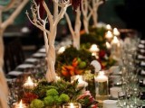 a woodland inspired wedding tablescape with trees, greenery, blooms and candles