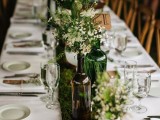 a woodland wedding tablescape with a moss runner, greenery and blooms in vases and tags and blooms for place settings