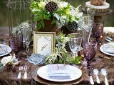 a woodland meets vintage tablescape with a feather table runner, succulents, air plants, cages and purple glasses