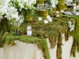 a spring woodland wedding tablescape with a moss tablecloth, fresh white blooms and lots of candles