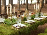 a woodland wedding tablescape with a moss tablecloth, greenery, candles in gold candleholders and an elegant clock