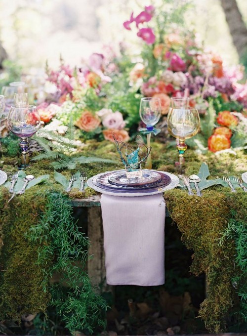 a lush forest wedding table setting with a moss tablecloth, lush blooms and ferns