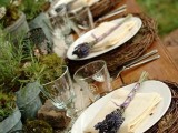 a wedding tablescape of twiggy placemats, moss, greenery, rocks and colored glasses plus lavender
