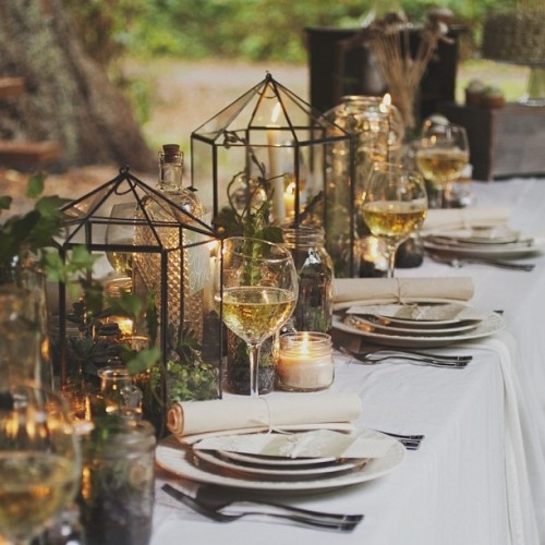 greenery in terrariums, candles and moss on the table make it woodland-like