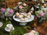 a woodland wedding tablescape with a moss tablecloth, some purple and pink romantic florals, gold cutlery and amber glasses