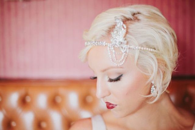 An art deco bridal headpiece of rhinestones and an embellished feather is a lovely and bold accent