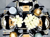 a chic wedding tablescape with a white rose centerpiece, large candles and ornaments and gold cutlery
