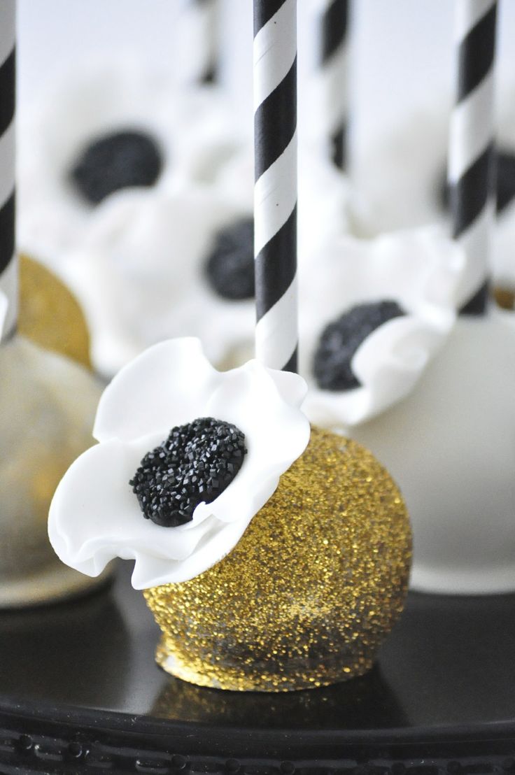 gold glitter cake pops with black and white blooms on top is a fun dessert idea