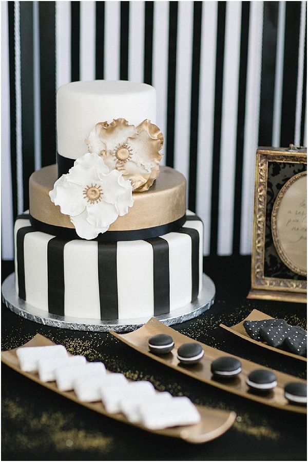 A gold and striped black and white wedding cake with sugar blooms