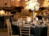 a black, white and gold wedding tablescape with striped napkins, a lush white bloom centerpiece, white candles and a gold frame
