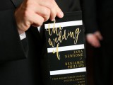 a striped black and white wedding invitation with gold calligraphy