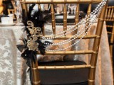 a black chair with beads, faethers, lace and brooches