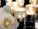 a black tablecloth and sparkling candle holders plus white roses for table decor
