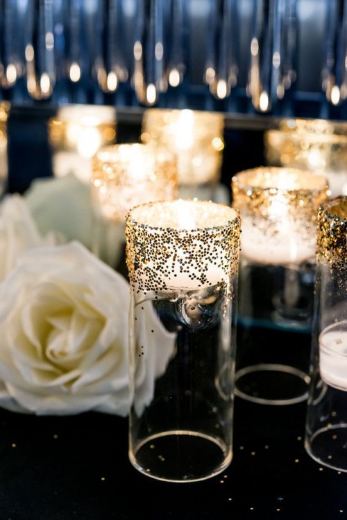 a black tablecloth and sparkling candle holders plus white roses for table decor